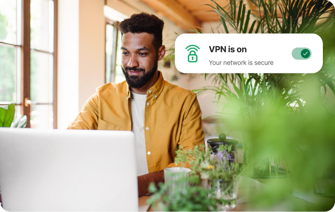 Egy növényekkel körülvett férfi egy laptopra mosolyog